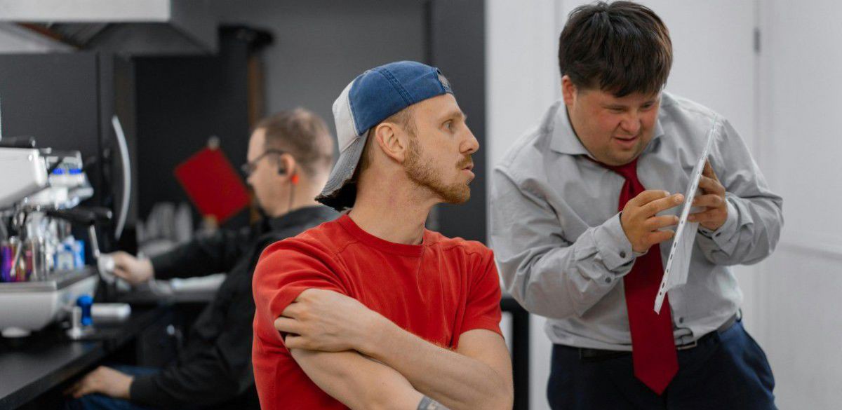 Mensch mit Down Syndrom im Gespr&auml;ch mit Kollegen.