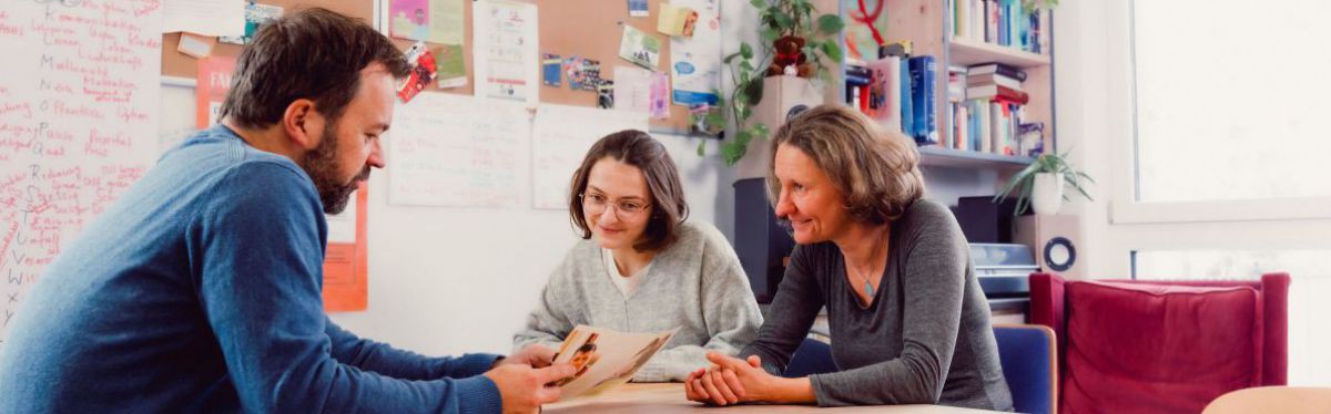Beratungssituation mit drei Personen in einem Büro.