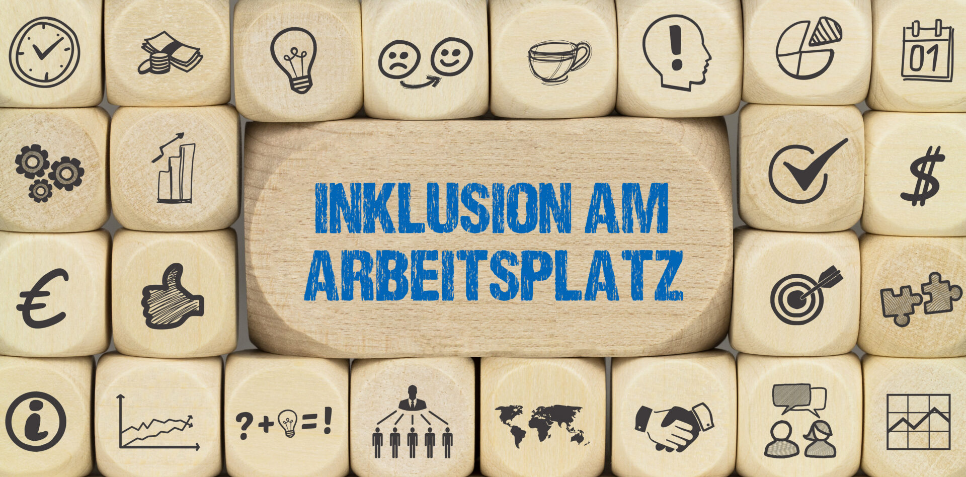 Würfel mit verschiedenen Symbolen, in der Mitte ein Holzblock mit dem Text "Inklusion am Arbeitsplatz".