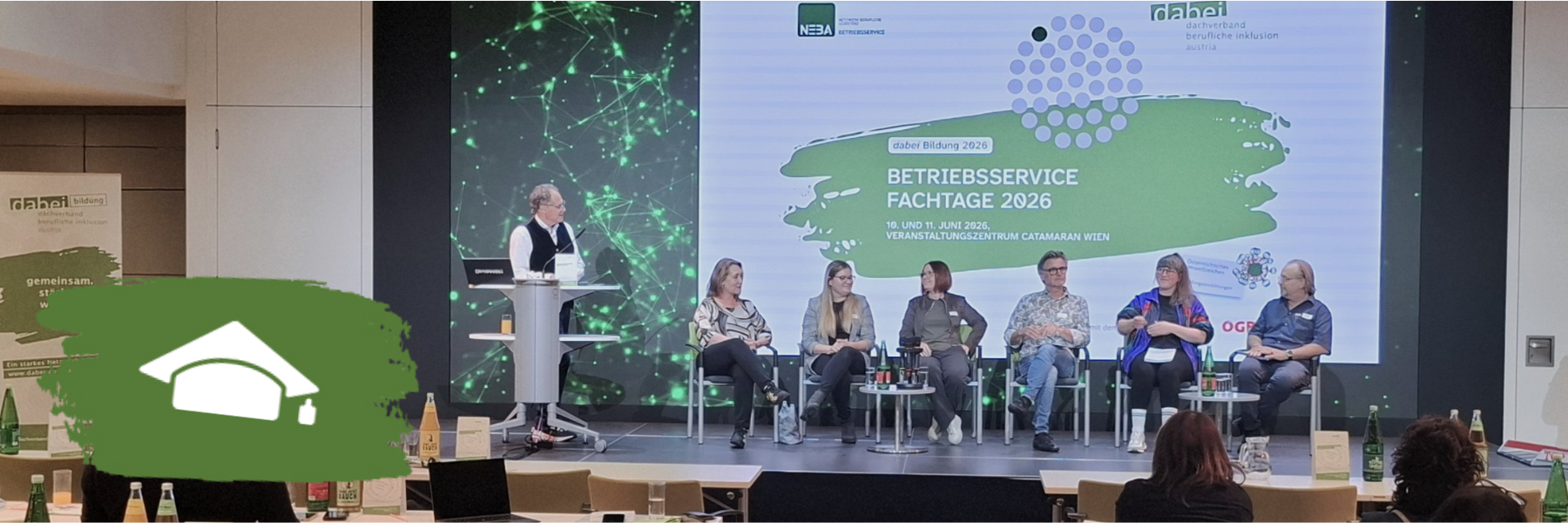 Blick vom Publikum auf das Posium der dabei-austria Betriebsservice Fachtage. Auf der Bühne sitzen sechs Personen auf Sesseln, links von ihnen steht ein Moderator am Pult.