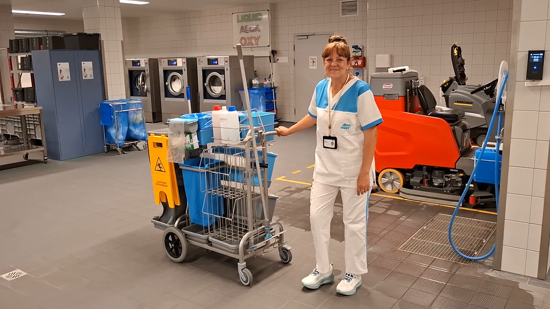 Eine Reinigungskraft steht imt ihrem Servicewagen in der Wäscheabteilung eines Spitals.